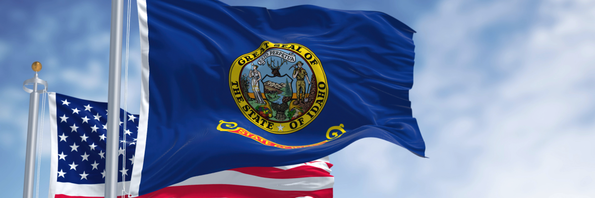 Picture of the flags of the United States and the State of Idaho against a blue sky with faint white clouds